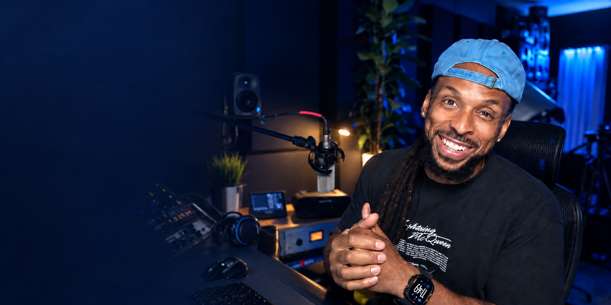 Wavy Wayne smiling in his blue-lit recording studio